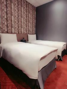 台北耘荷居 Yún Inn的配有白色床单的客房内的两张床