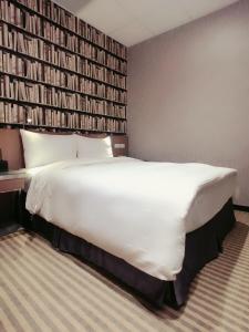 台北耘荷居 Yún Inn的一张大白色的床,位于一个书墙的房间