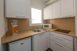 布拉内斯Apartamentos AR Muntanya Mar的小厨房配有白色橱柜和水槽