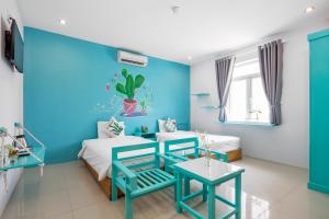 岘港RAON Apartment & Hotel的蓝色和白色的客房配有两张床和一张桌子