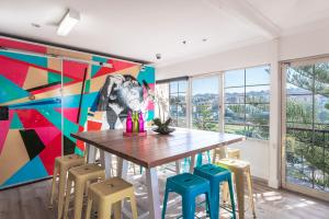 悉尼库吉海滩灵猴旅舍的用餐室配有桌椅和壁画