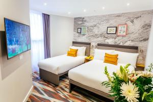 伦敦奥利弗广场酒店的一间酒店客房,设有两张床和电视