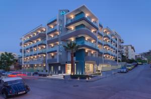 罗希姆诺Melrose Rethymno by Mage Hotels的蓝色的建筑,有汽车停在停车场
