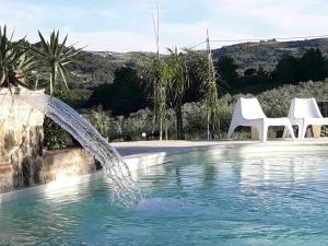 卡拉塔菲米迪塞杰斯塔住宿加早餐旅馆的一个带两把白色椅子的游泳池以及一个喷泉