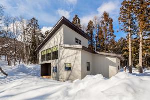 白马村Solar Chalets by Hakuba Hospitality Group的树林中的雪地房子