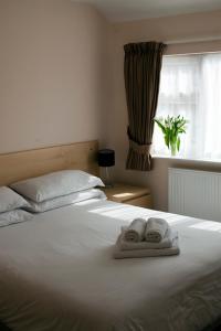 布伦特伍德Brentwood Guest House Hotel的卧室配有白色床和毛巾