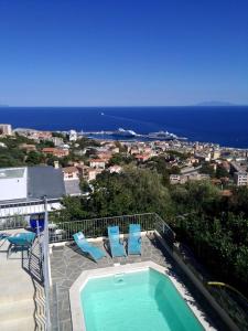 巴斯蒂亚Villa Patrizia的一个带两把蓝色椅子的游泳池以及大海