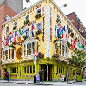 都柏林Gogartys Temple Bar Hostel的前面有旗帜的黄色建筑