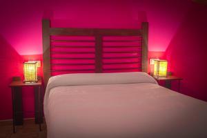 GalveHotel Rural Casa La Era的卧室配有白色床和粉红色照明