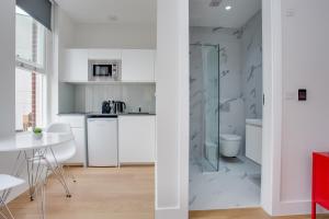 伦敦Chapel Market Serviced Apartments by Concept Apartments的厨房配有白色橱柜和玻璃淋浴间。