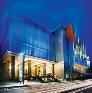 万隆Golden Flower by KAGUM Hotels的一座大型玻璃建筑,上面有蓝色的灯光