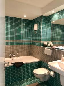 黑灵斯多夫Mini-Reihenhaus "Alte Buchdruckerei"的绿色瓷砖浴室设有浴缸和卫生间