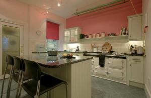 牛顿莫尔Netherwood House的一间带红色墙壁的厨房和一个带椅子的柜台