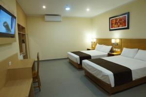 普卡尔帕Águila Dorada Selva Hotel的酒店客房设有两张床和一台平面电视。
