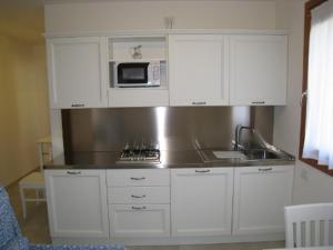 平佐洛Sillia Appartamenti的厨房配有白色橱柜、水槽和微波炉