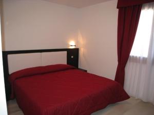 平佐洛Sillia Appartamenti的窗户客房内的一张红色的床