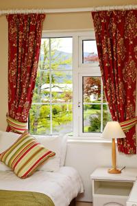 基拉尼阿什维尔旅馆的一间卧室配有红色窗帘、一张床和窗户