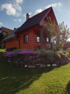 兹蒂尔Chalúpka u Babičky的一座带石墙和紫色花卉的圆木房子