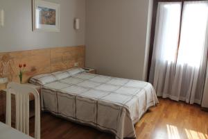 扎鲁亚斯Pensión Lagunak的一间卧室配有一张床、一张桌子和一个窗户。