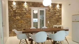 Merchia BeachSundance Suites Mykonos的一间设有石墙和木桌及椅子的用餐室