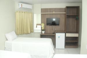 ItaitubaHotel Acai的酒店客房设有床、电视和电视架。