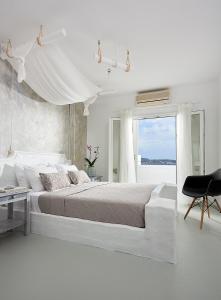 阿达玛斯米洛斯酒店的白色的卧室设有一张大床和一个窗户