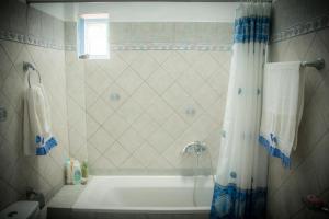 安坡里奥圣托里尼Katsinaros House的带浴缸和淋浴帘的浴室