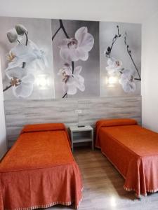耶斯特耶斯特酒店的配有两张床铺的客房,墙上装饰有橙色床单和鲜花