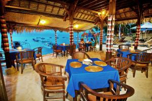 蓝梦岛郎邦巴厘岛小屋酒店的一间设有桌椅并享有水景的餐厅