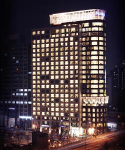 首尔首尔中心辉盛坊国际公寓的一座高大的建筑,晚上有照明窗户