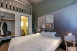 蒙托邦B&B HOTEL Montauban的卧室配有一张白色大床和一把椅子