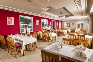 马赫迪耶Hotel Club El Borj的一间设有白色桌椅和红色墙壁的餐厅