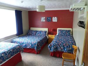 东迪勒姆Lynn Hill Guest House的红色墙壁客房的两张床