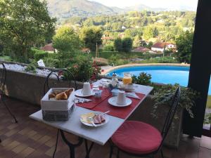 亚斯凯恩Guest house Maison Iratzean的一张带早餐食品的桌子,享有游泳池的景色