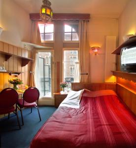 阿姆斯特丹纳迪亚酒店的一间卧室配有一张红色大床和一张桌子及椅子
