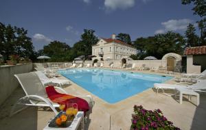 圣保罗－代斯皮圣让庄园酒店的一座带白色椅子的游泳池和一座建筑