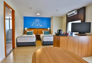 塔瓜汀加塔瓜汀加康福特酒店的酒店客房设有两张床和一台平面电视。