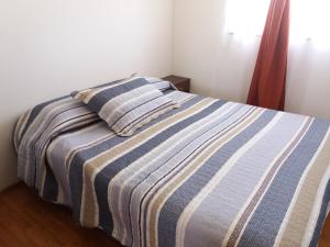 弗鲁蒂亚尔Cabañas M y M Frutillar的一张带条纹毯子和两个枕头的床