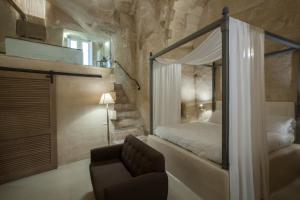 马泰拉彼得拉艾露酒店的一间卧室配有一张天蓬床和一把椅子