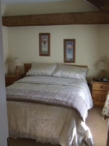 金塞尔Inglenook的卧室内的一张床位,墙上挂着两盏灯和两张照片