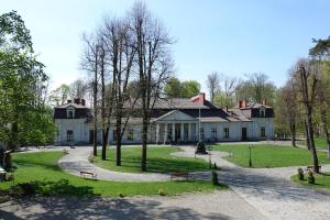 RopaGościniec Dworski w Ropie - Pokoje gościnne的前面有树木的大白色房子