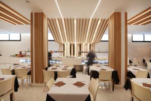 贝尼多姆巴西酒店的一间设有白色桌子和白色椅子的餐厅,以及一间供个人用餐的餐厅