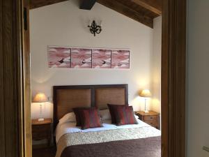 Horcajuelo de la SierraAL VIENTO, Alojamiento & Turismo Rural Horcajuelo的一间卧室配有一张带两盏灯的床,墙上挂着一张照片