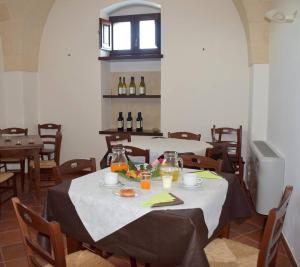 利扎诺Masseria San Vito - Agriturismo的用餐室配有带食品和葡萄酒瓶的桌子