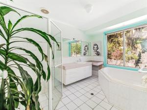 CooranNoosa Hinterland Spectacular Boutique Guesthouse的带浴缸、卫生间和植物的浴室