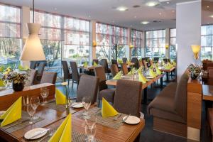 科隆Essential by Dorint Köln-Junkersdorf的餐厅设有桌椅,配有黄色餐巾