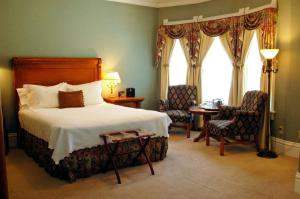 马尼温泉派克峰悬崖屋酒店的一间卧室配有一张床、两把椅子和一个窗户