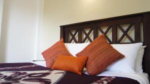 努沃勒埃利耶苏里亚宾客旅馆的一张带橙色和白色枕头的床