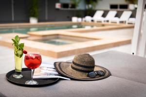 汤斯维尔汤斯维尔格兰公寓式酒店的池畔桌子上的帽子和饮料