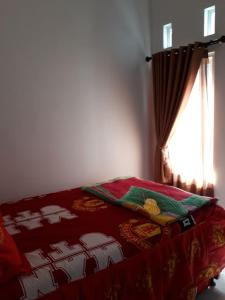 巴图Villa Puncak Garuda A5的一张带红色毯子和窗户的床
